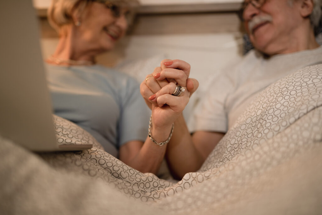 Sécurité et intimité : deux besoins essentiels à respecter Closeup Affectionate Senior Couple Holding Hands While Lying Down Bed Evening 1024x683